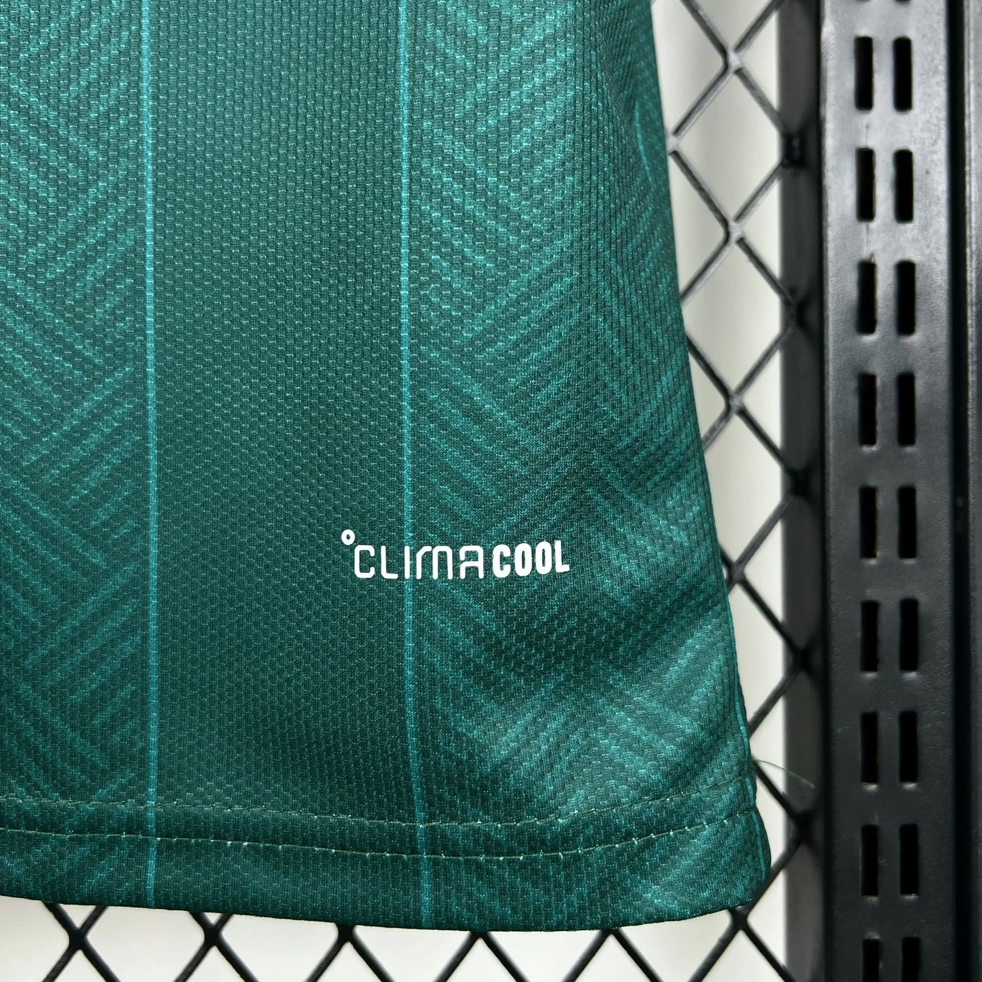 Detalle del acabado inferior de la camiseta y la textura del material transpirable de la equipación verde.