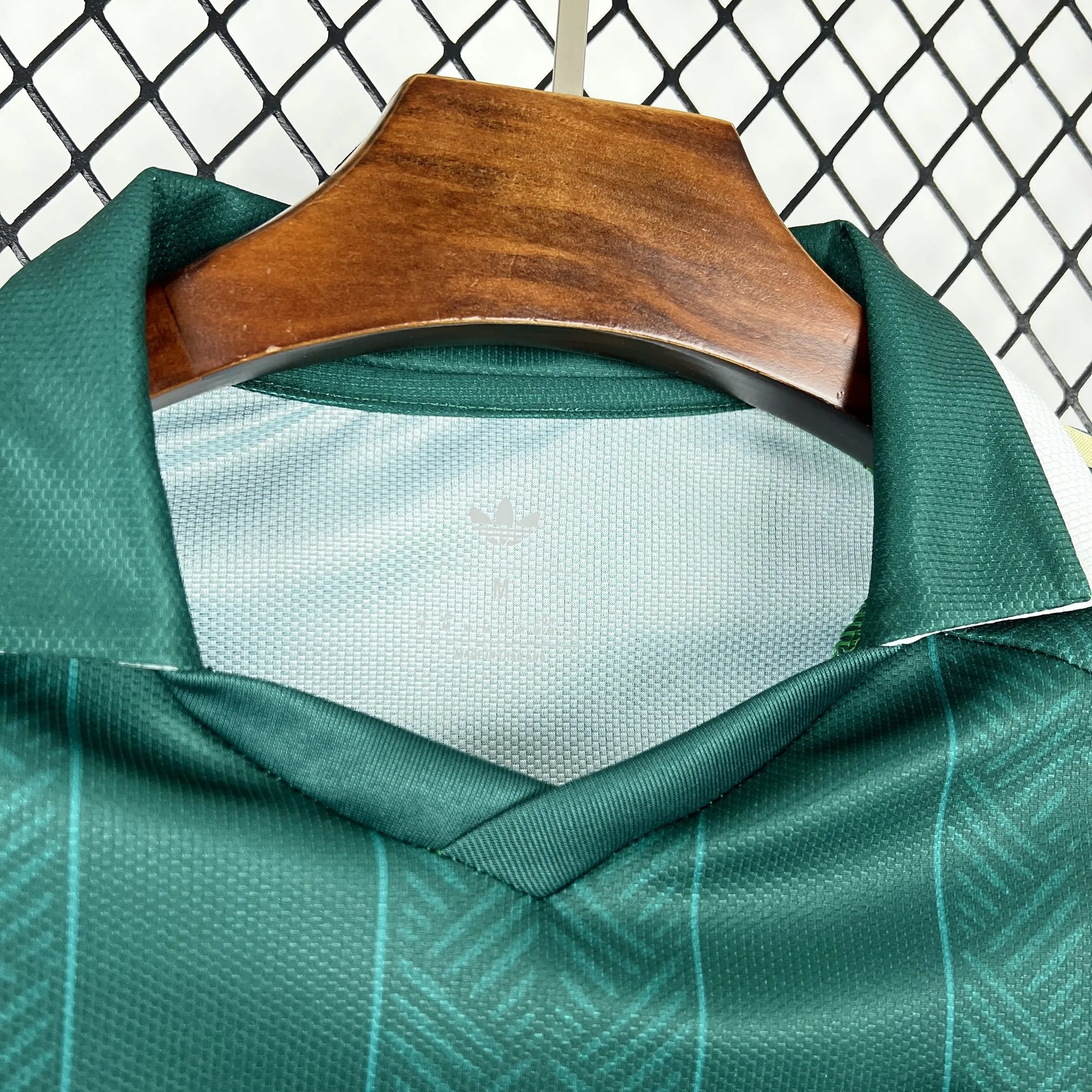 Detalle del cuello redondo en color verde con acabados de alta calidad y gráficos técnicos en el interior.