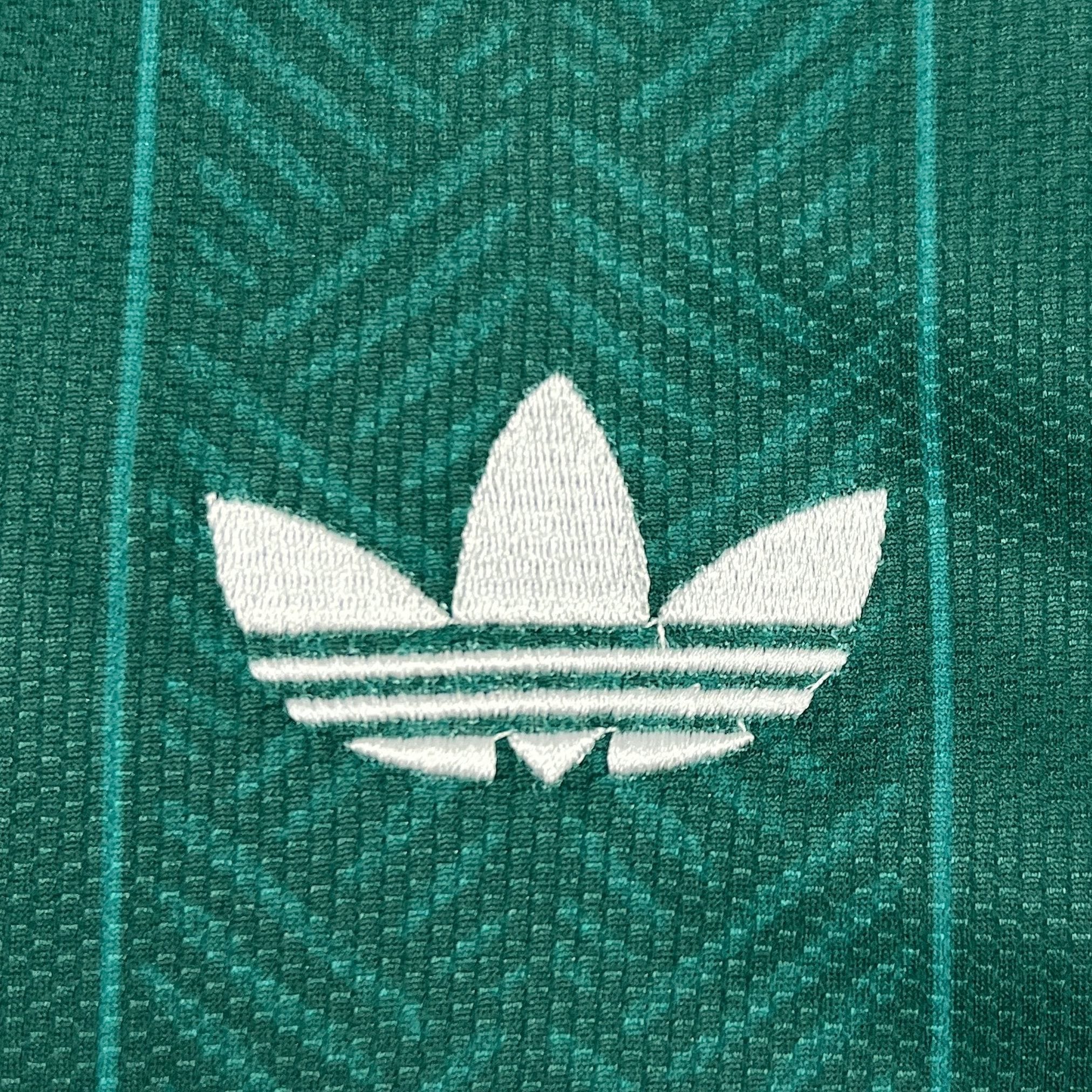 Detalle de logotipo decorativo bordado en color amarillo sobre el tejido técnico verde de la camiseta de Sudáfrica.