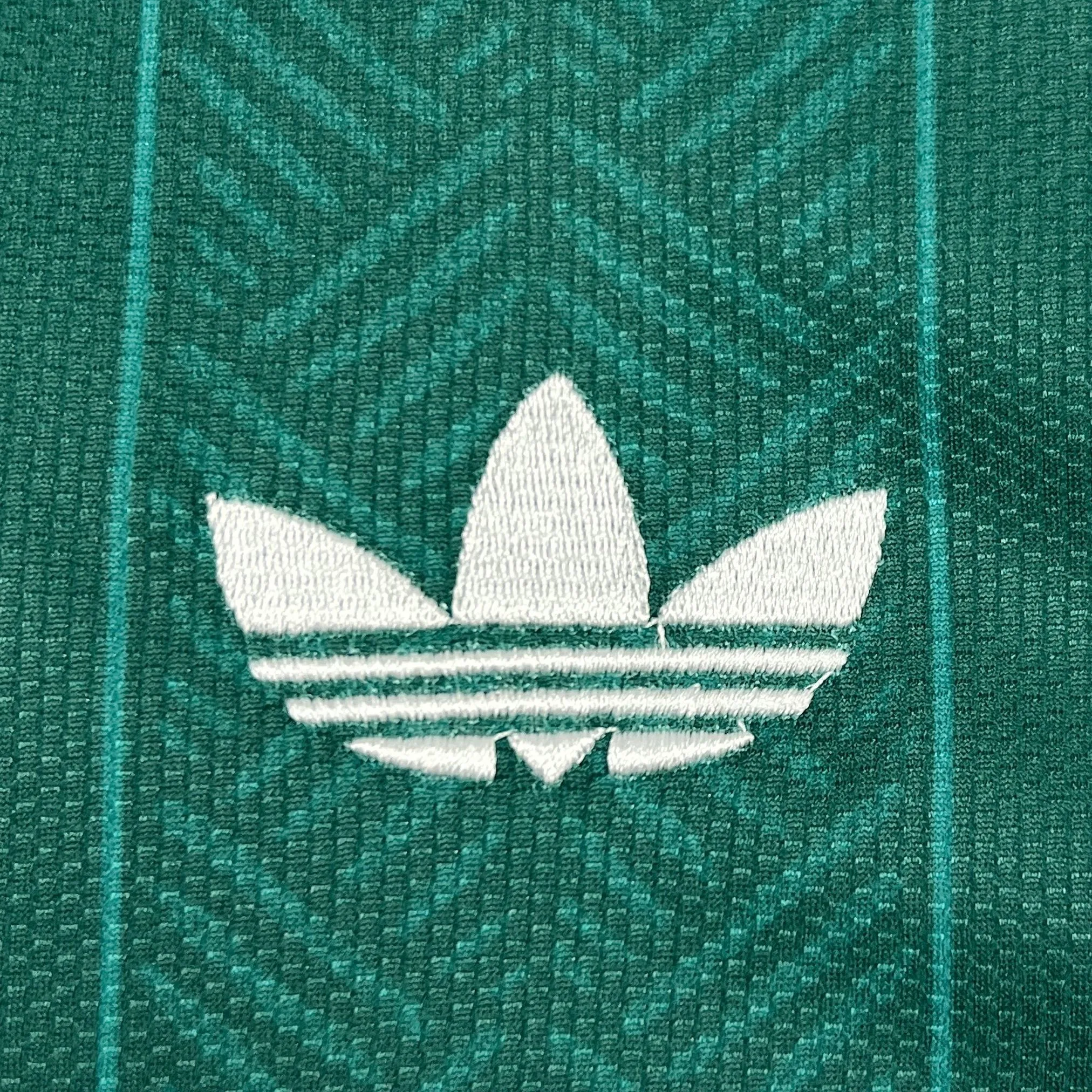 Detalle de logotipo decorativo bordado en color amarillo sobre el tejido técnico verde de la camiseta de Sudáfrica.