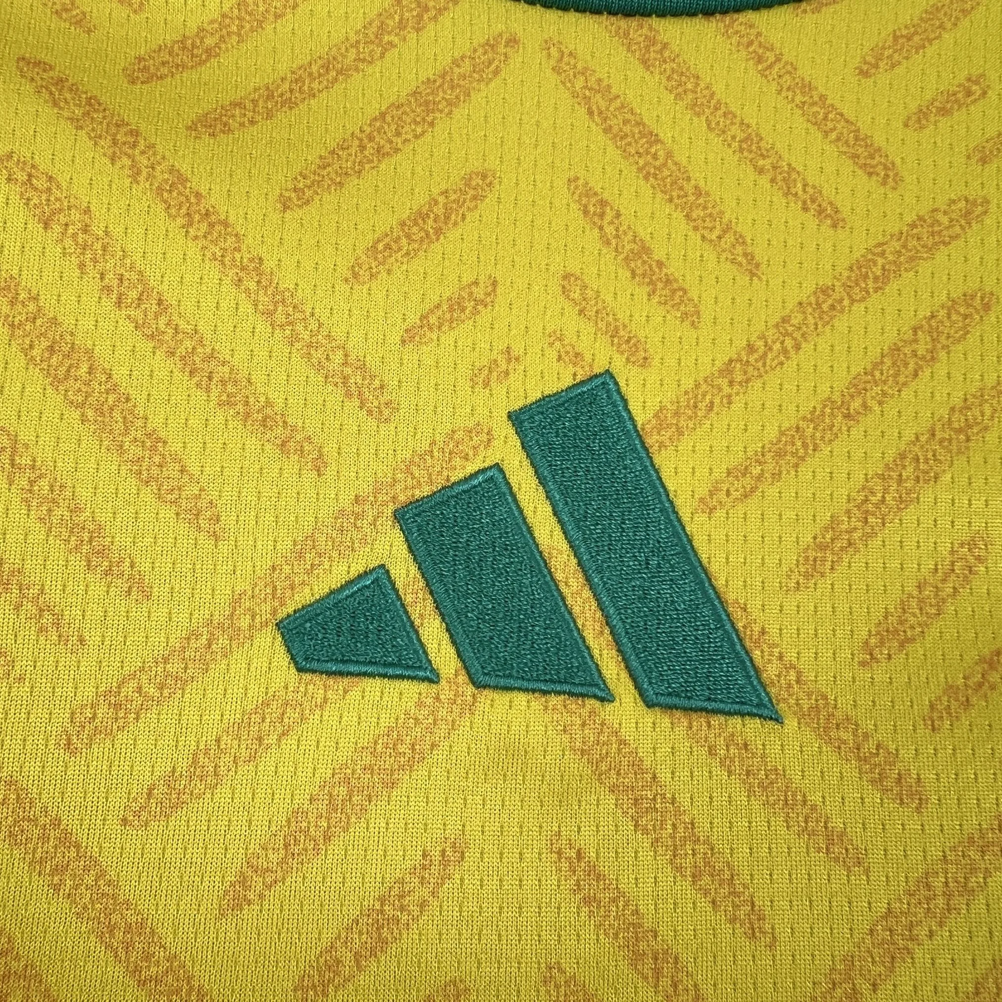 Detalle decorativo bordado en color verde sobre el tejido técnico amarillo de la camiseta de Sudáfrica.
