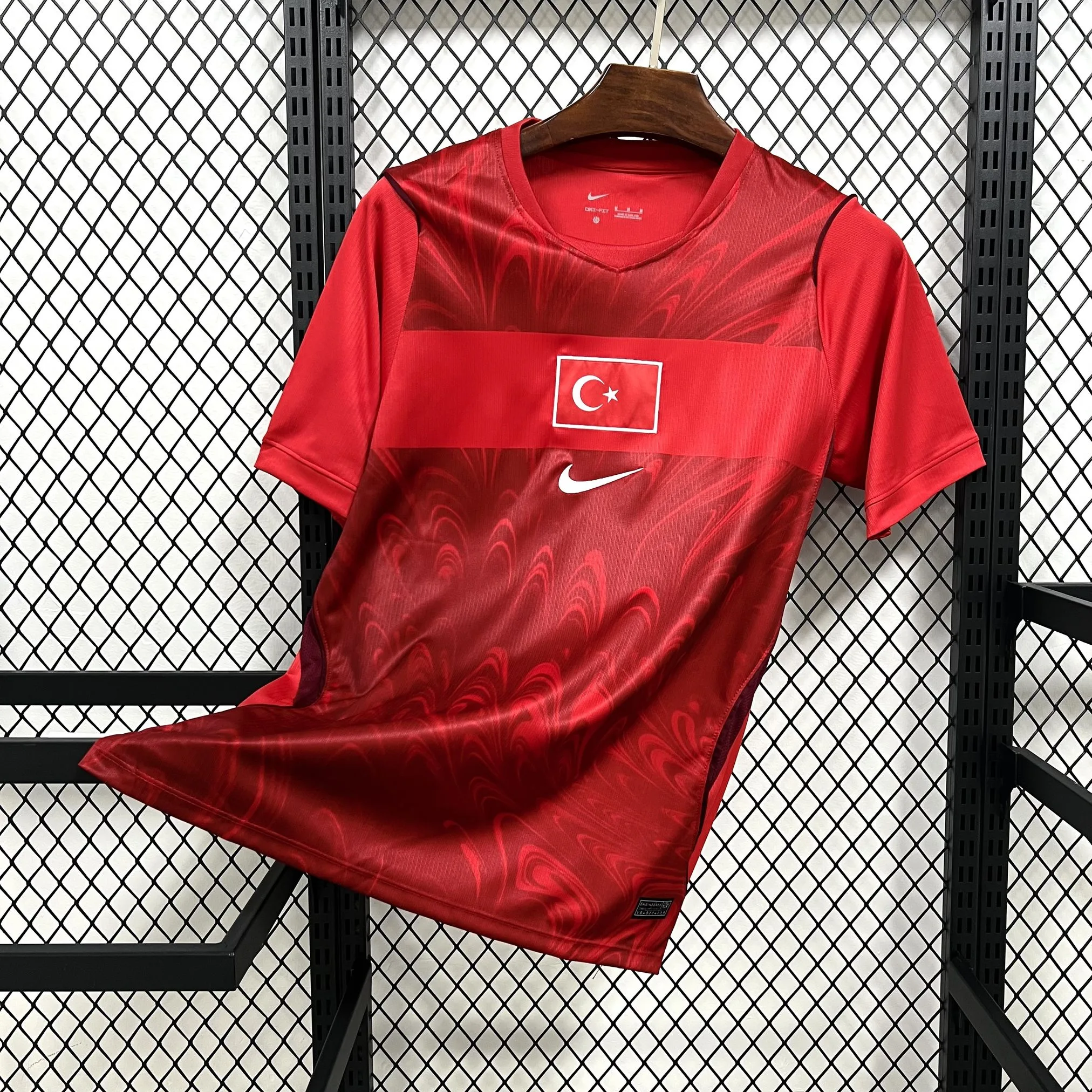 Imagen frontal completa de la camiseta visitante de Turquía, color rojo con sutiles patrones geométricos y detalles blancos.