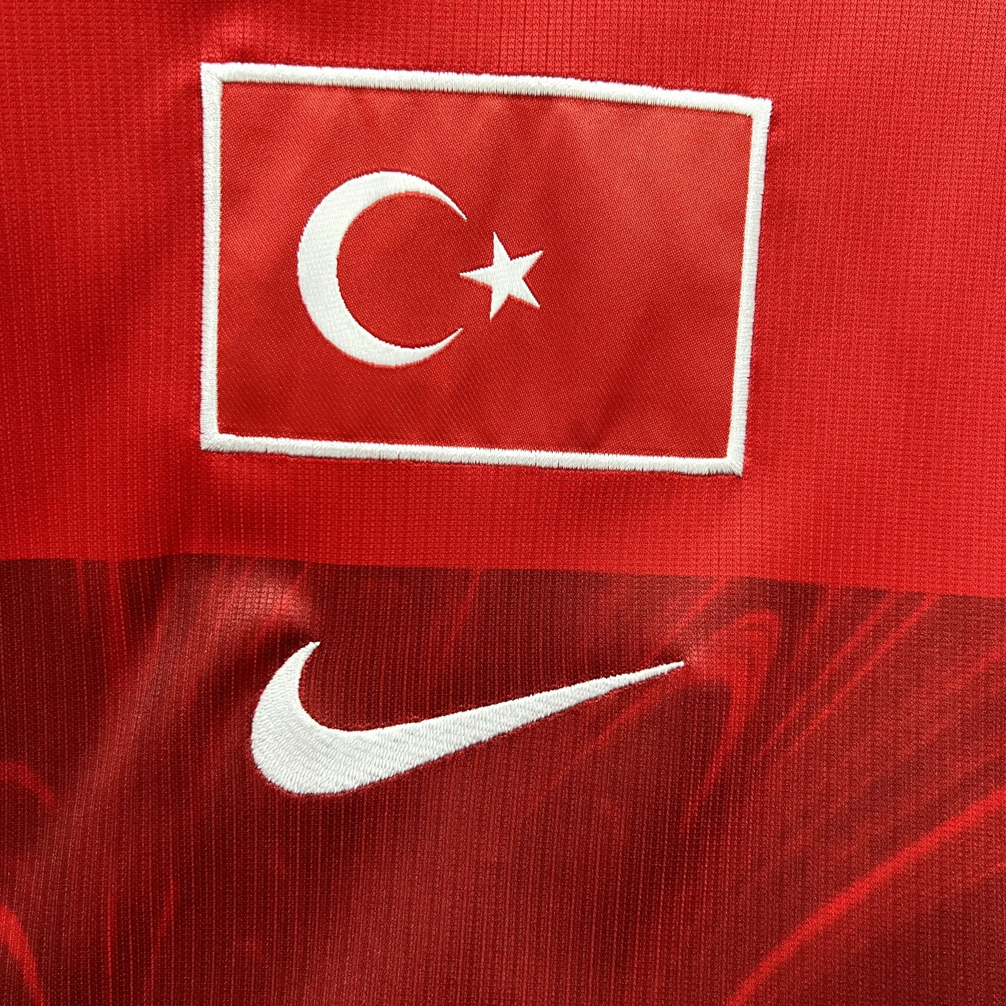 Detalle decorativo bordado en color blanco sobre el tejido técnico rojo de la camiseta de la selección de Turquía.