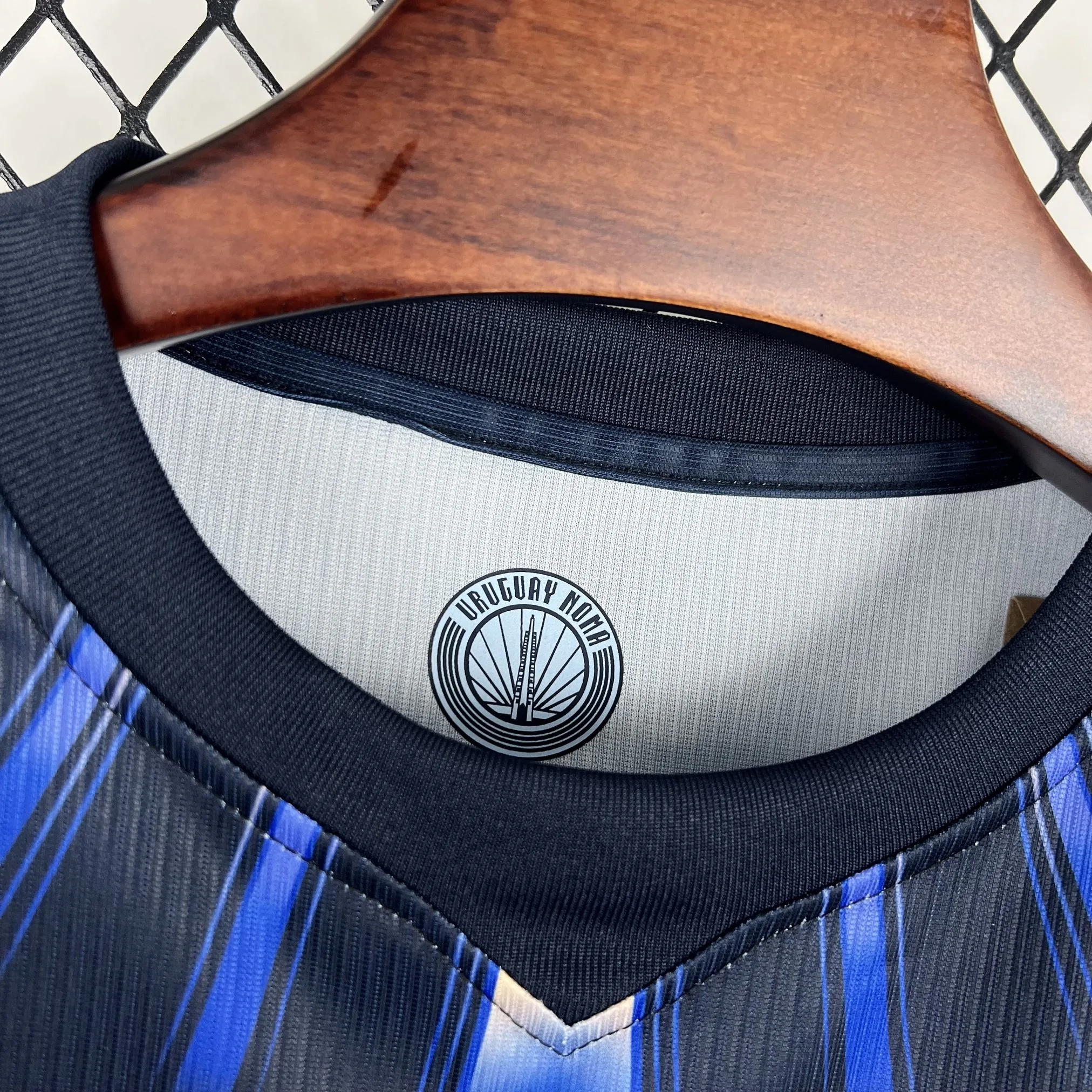 Detalle del cuello redondo con un diseño bicolor azul celeste y blanco, resaltando los logotipos técnicos en el interior.