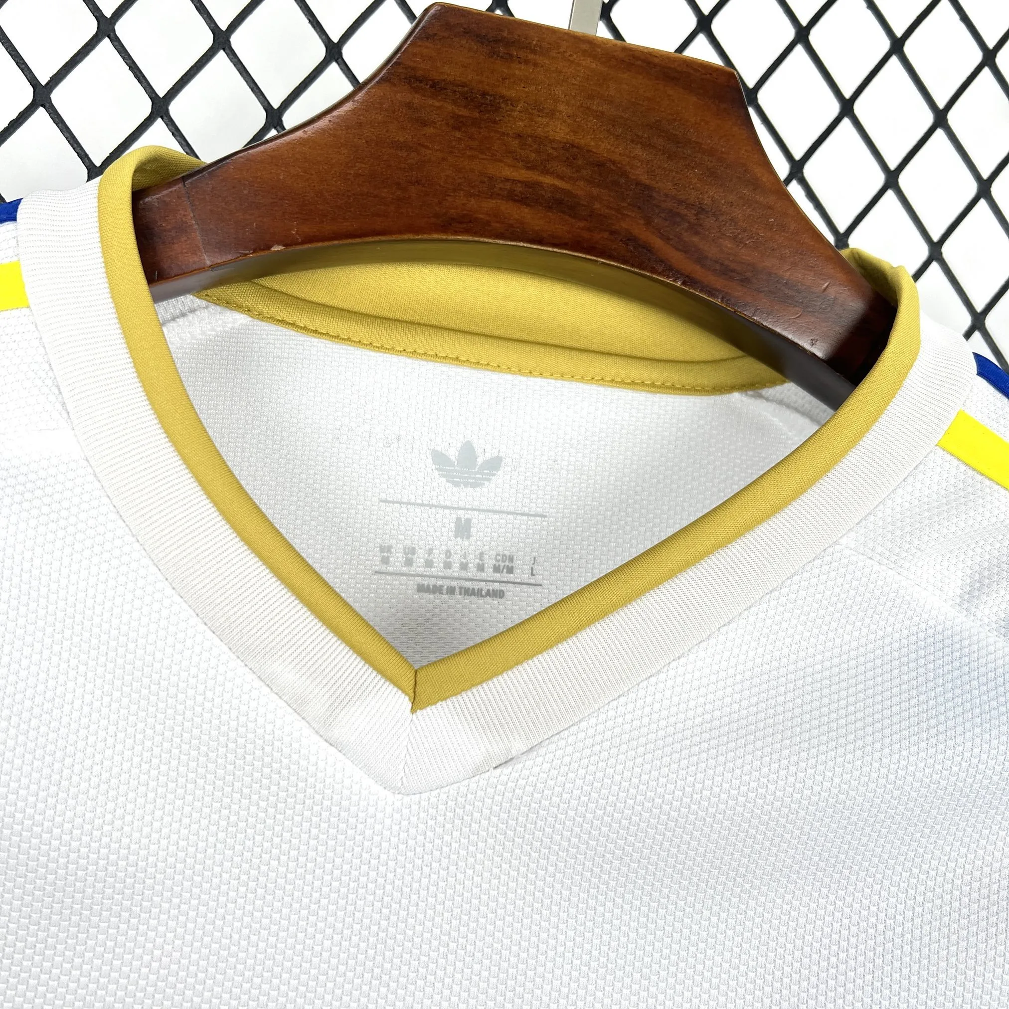 Detalle del cuello redondo blanco con finos acabados en azul y amarillo de la segunda equipación venezolana.