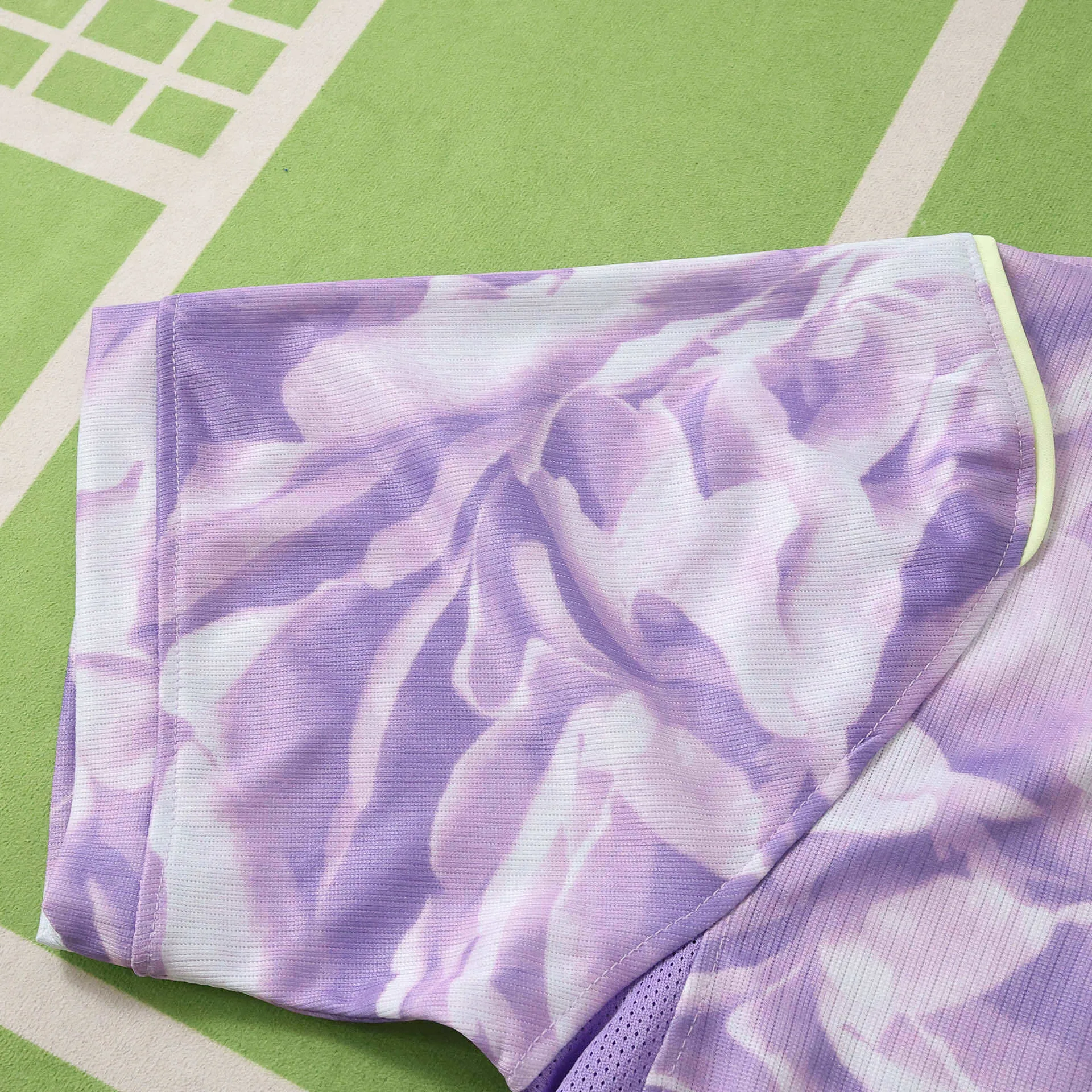 Primer plano de la manga con remate elástico en color verde lima y un patrón gráfico abstracto en tonos lila y morado.