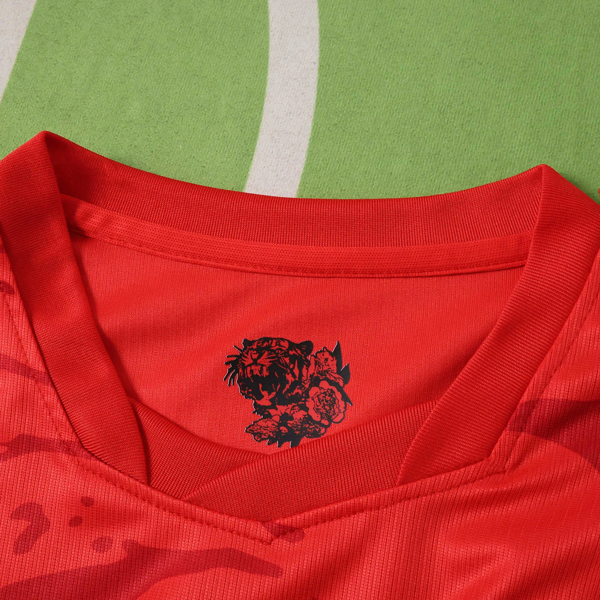 Detalle del cuello redondo rojo resaltando la ilustración de un tigre negro y flores nacionales en el interior de la prenda.