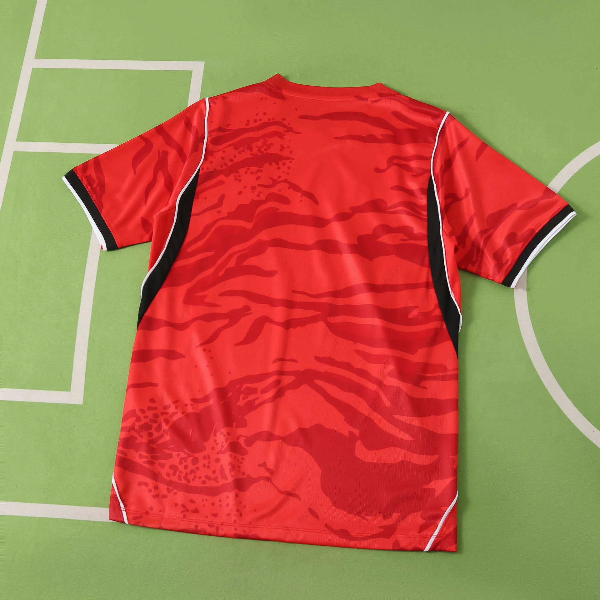 Vista posterior de la camiseta de Corea del Sur 2026, diseño rojo con patrón de camuflaje de tigre y paneles laterales en contraste.