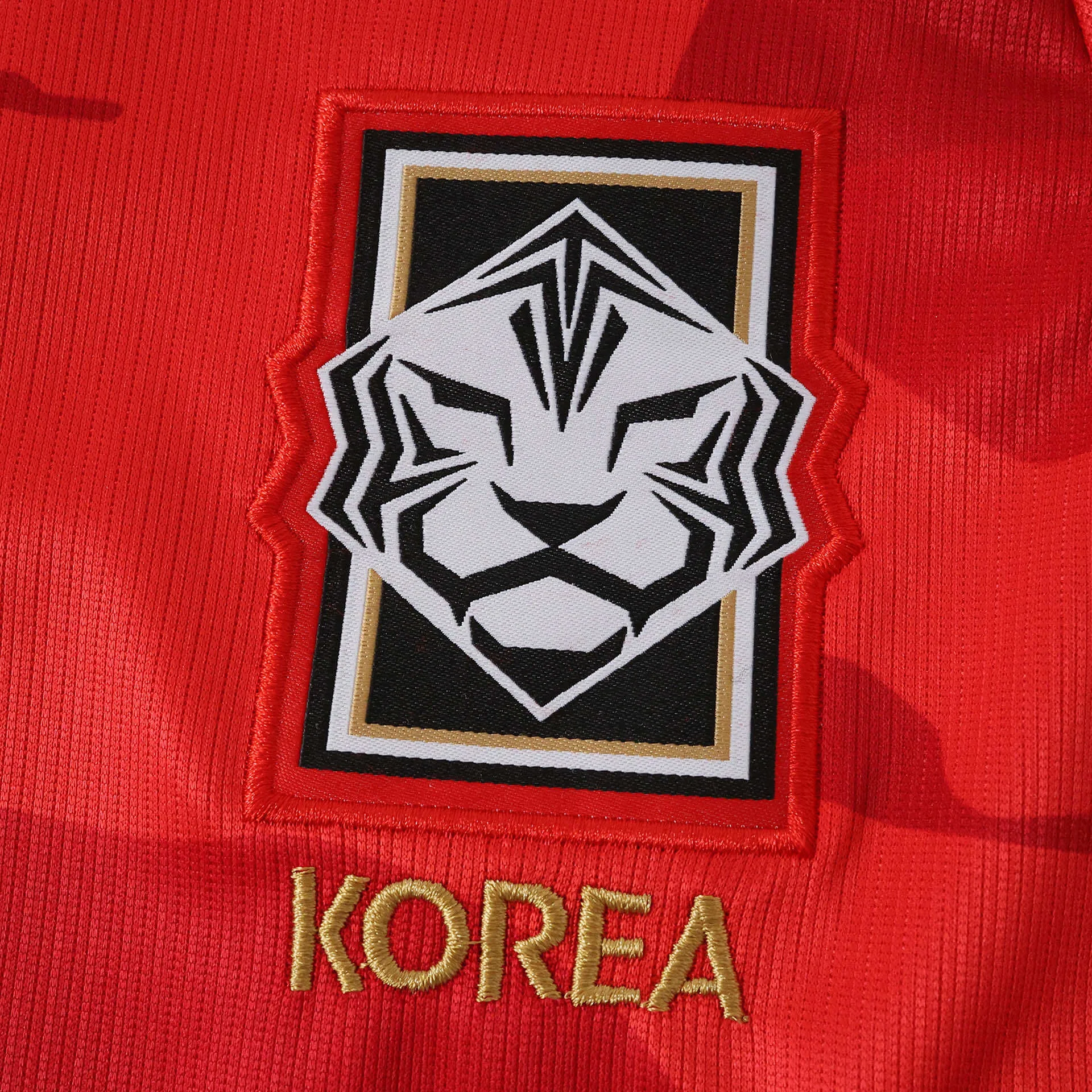 Primer plano del escudo de la Asociación de Fútbol de Corea con el diseño estilizado del tigre blanco bordado.