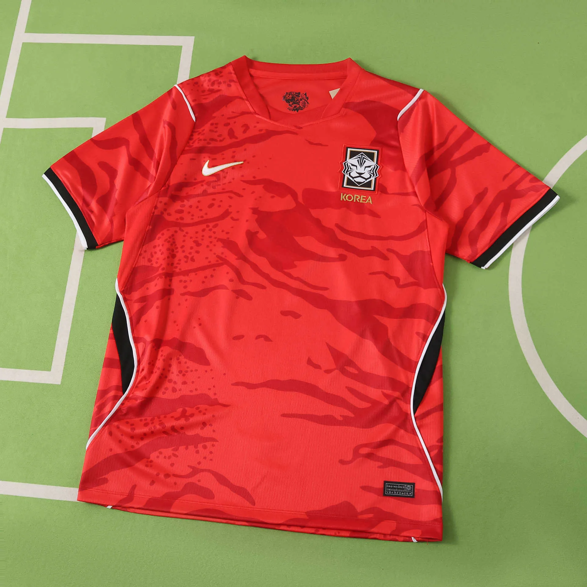 Imagen frontal completa de la camiseta local de Corea del Sur, color rojo vibrante con un patrón gráfico de zarpazos de tigre en tonos tonales.