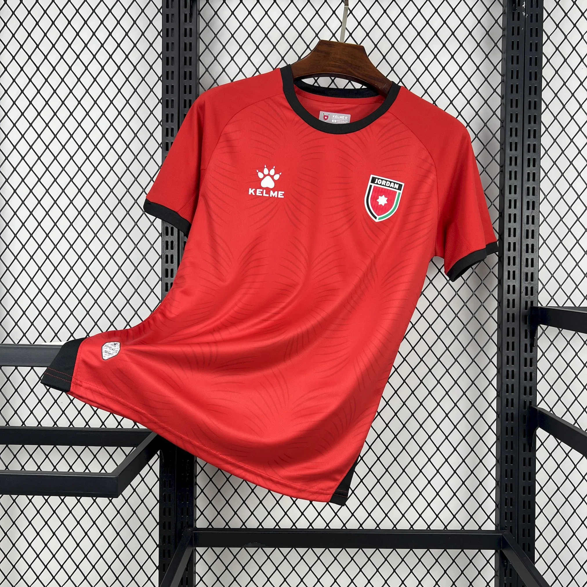 Imagen frontal completa de la camiseta visitante de Jordania para el Mundial 2026, color negro con detalles en rojo.