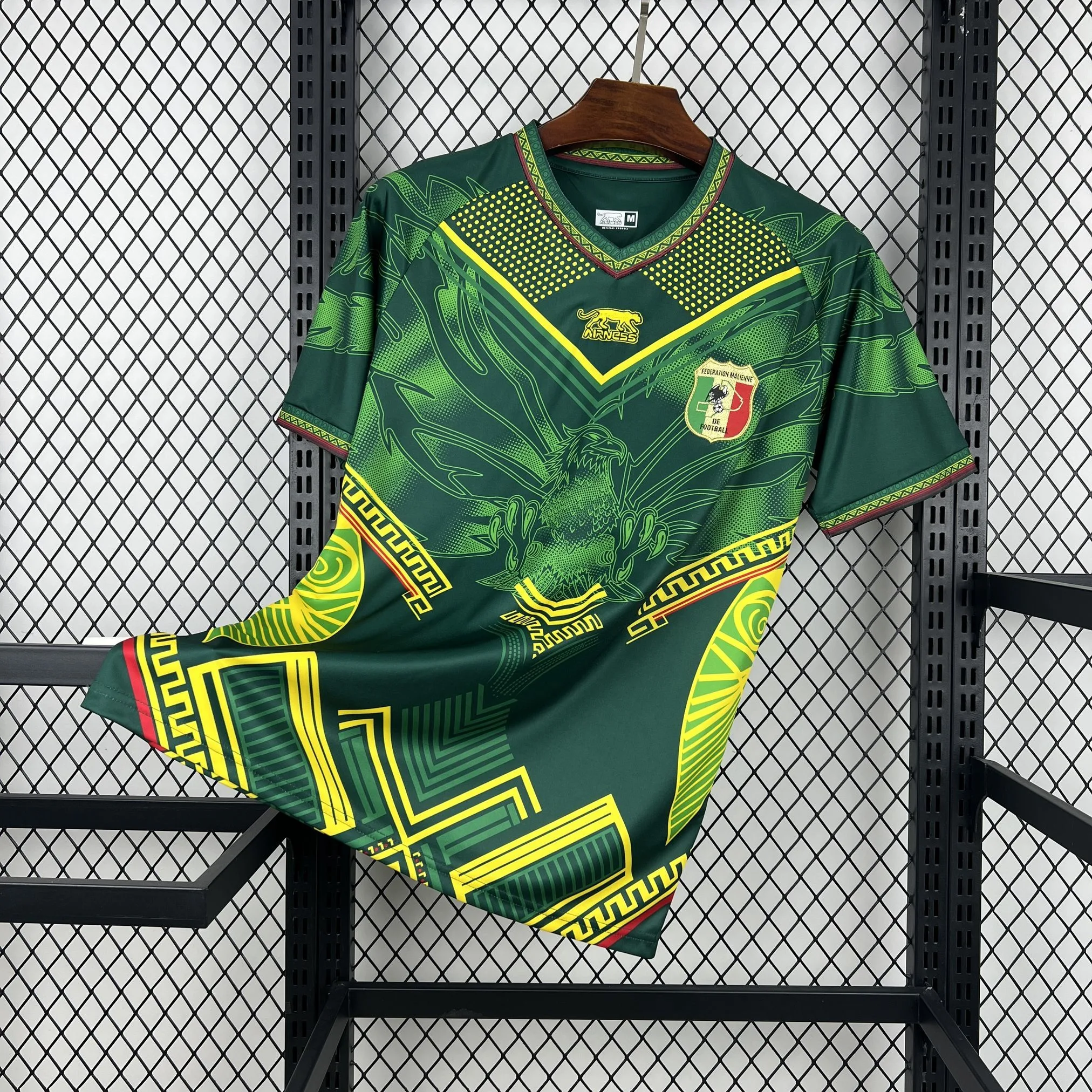 Imagen frontal completa de la camiseta visitante de Mali, color blanco con un imponente gráfico de águila en el centro con los colores de la bandera nacional.