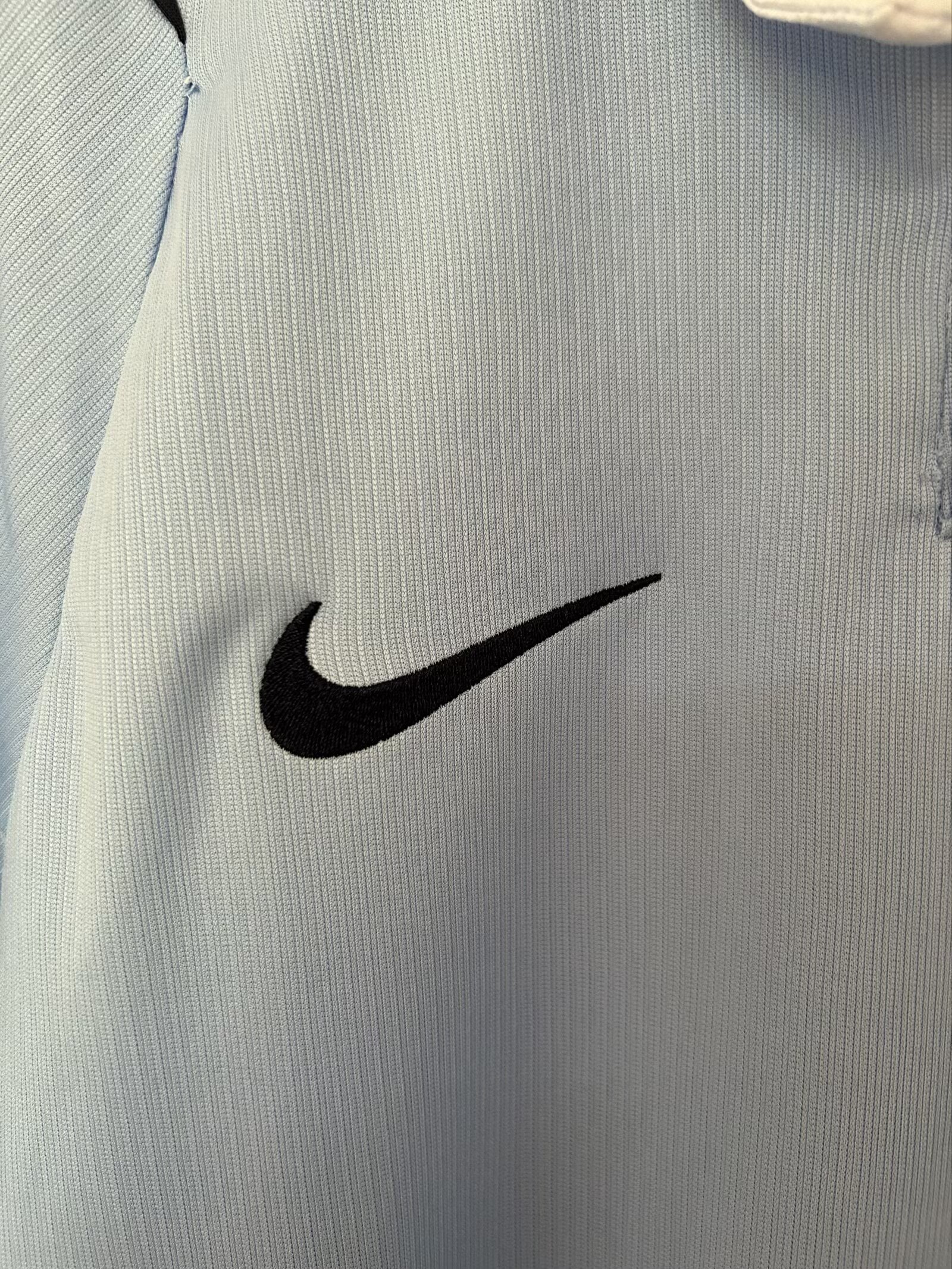 Detalle decorativo bordado en color negro sobre el pecho de la camiseta de la selección de Uruguay.