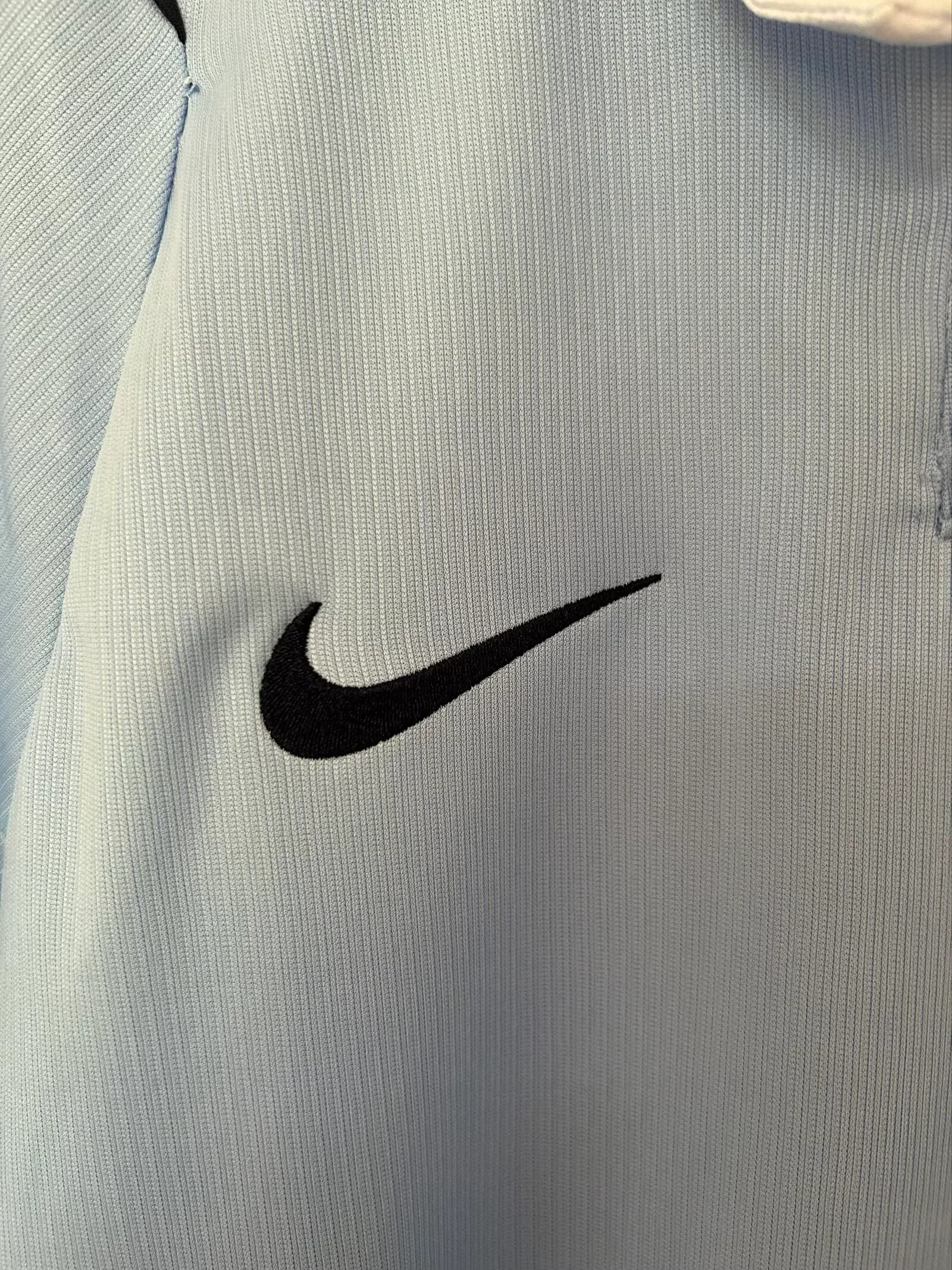 Detalle decorativo bordado en color negro sobre el pecho de la camiseta de la selección de Uruguay.